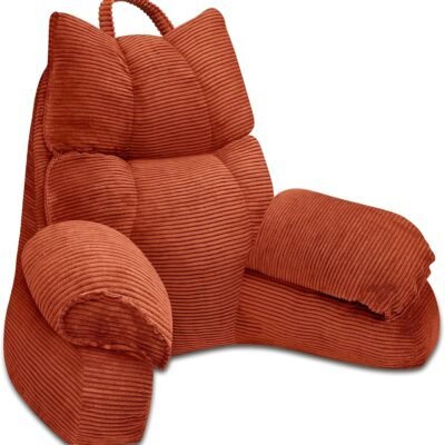 Rust-orange corduroy reading pillow with armrests and a top carry handle, shown on a white background.